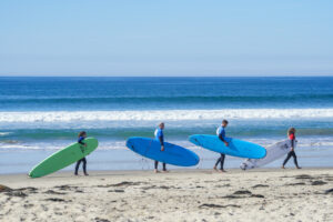 Three surfers walking on the sand with the sea in the background