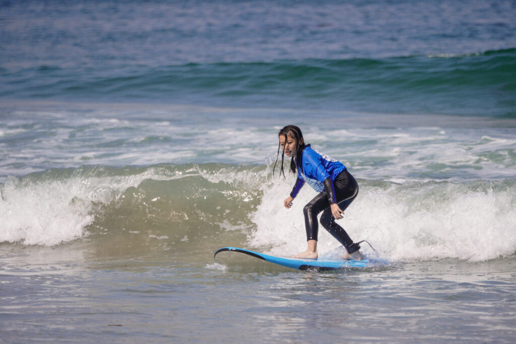 Child on top of a surfboard learning to surf